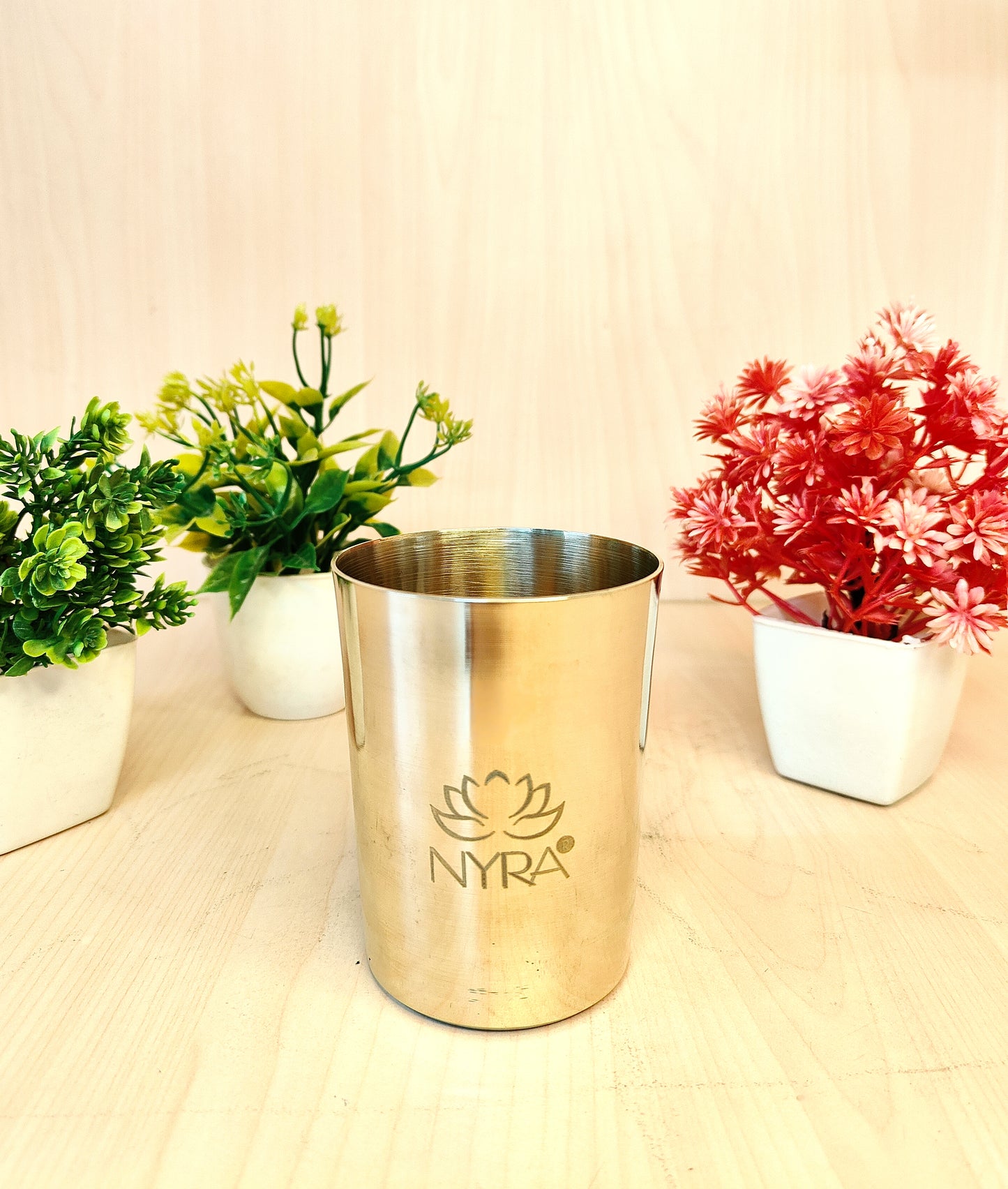 Gold cup with 'NYRA' logo on a light surface with plants in the background