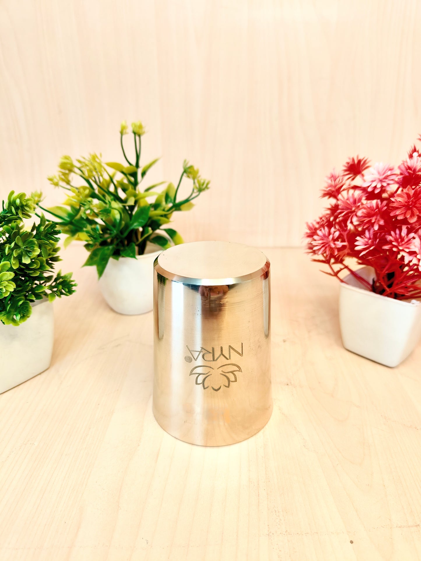 Gold cylindrical container with 'Nyan' branding on a wooden surface with plants in the background