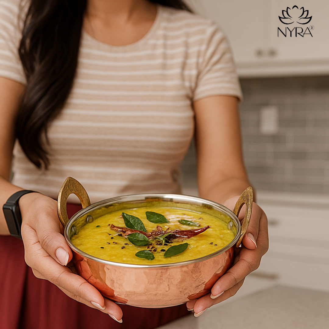 Person holding a bowl of yellow soup with Nyra logo in the corner