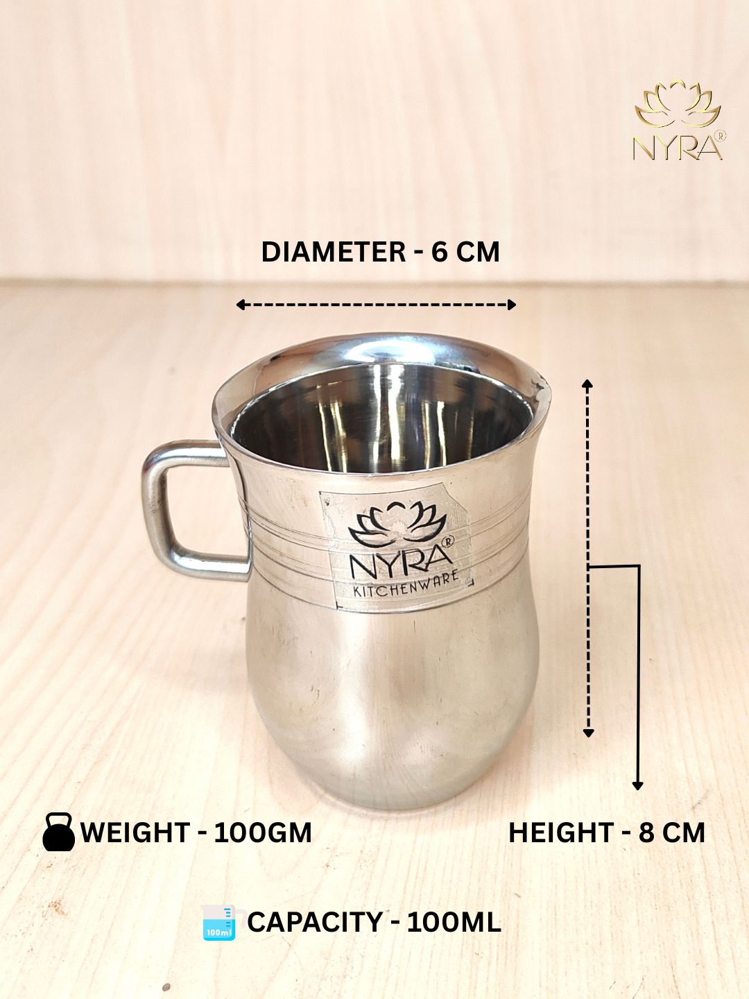 Stainless steel cup with NYRA Kitchenware branding, showing measurements and weight on a light wooden background.