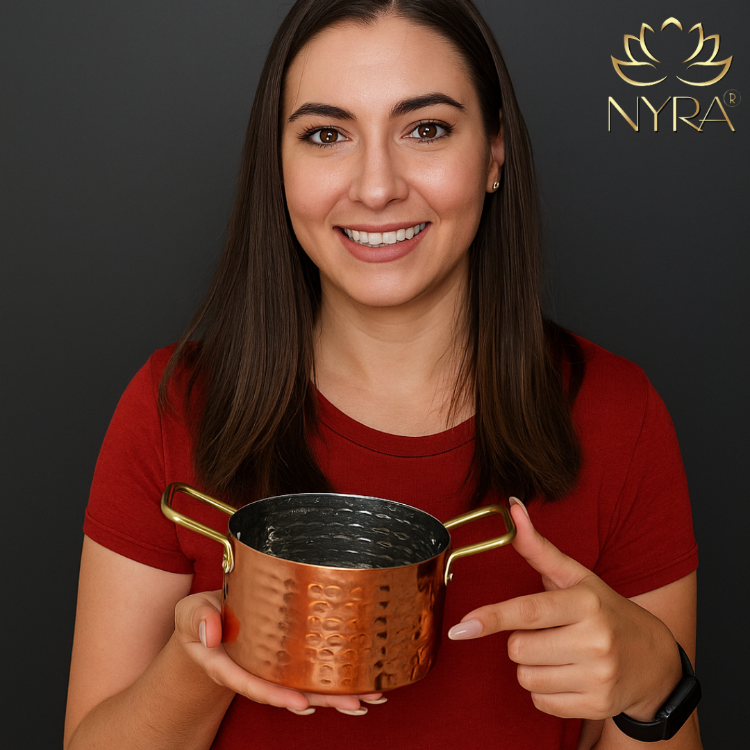 Woman holding a bronze-colored metal cup with 'Nyra' branding in the background