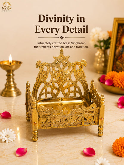 An ornate brass Singhasan idol for Lord Ganesha, beautifully carved with intricate details, displayed on a marble surface with a lit brass diya, marigold petals, and decorative flowers in the background. Text overlay reads 'Divinity in Every Detail' with the NYA brand logo in the top left corner.