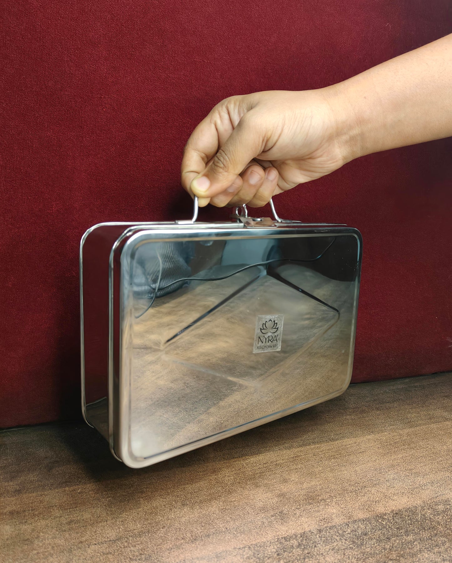 Metal CASH box with a visible brand logo held by a hand against a red background
