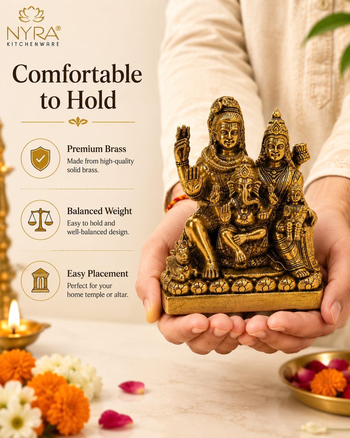 A person in a cream-colored kurta holds a small brass statue of a Hindu deity family group. The left side of the image features a promotional graphic with the brand 'Nyra Kitchenware' and text reading 'Comfortable to Hold' with feature icons.