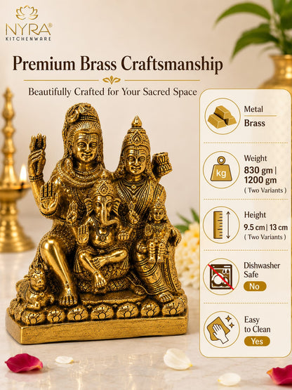 A brass statue of a Hindu family deity triad with Ganesha, shown on a light beige background with decorative props. The image includes the NYRA Kitchenware logo and a vertical list of product features on the right, including weight, height, dishwasher safe status, and ease of cleaning.