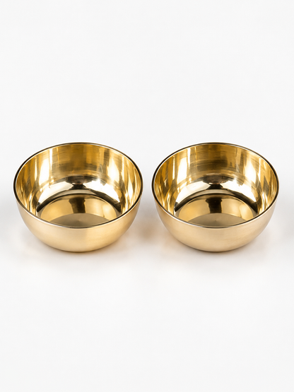 Two small round metallic bowls with a polished gold finish, shown side by side on a clean white background.