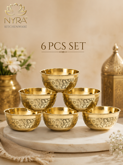 Six gold-toned engraved bowls arranged in a pyramid on a white marble platter, with decorative props and the text '6 PCS SET' and the NYRA Kitchenware logo.