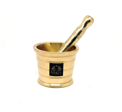 A brass mortar and pestle set with a black square logo plaque on the front of the mortar, photographed on a clean white background.