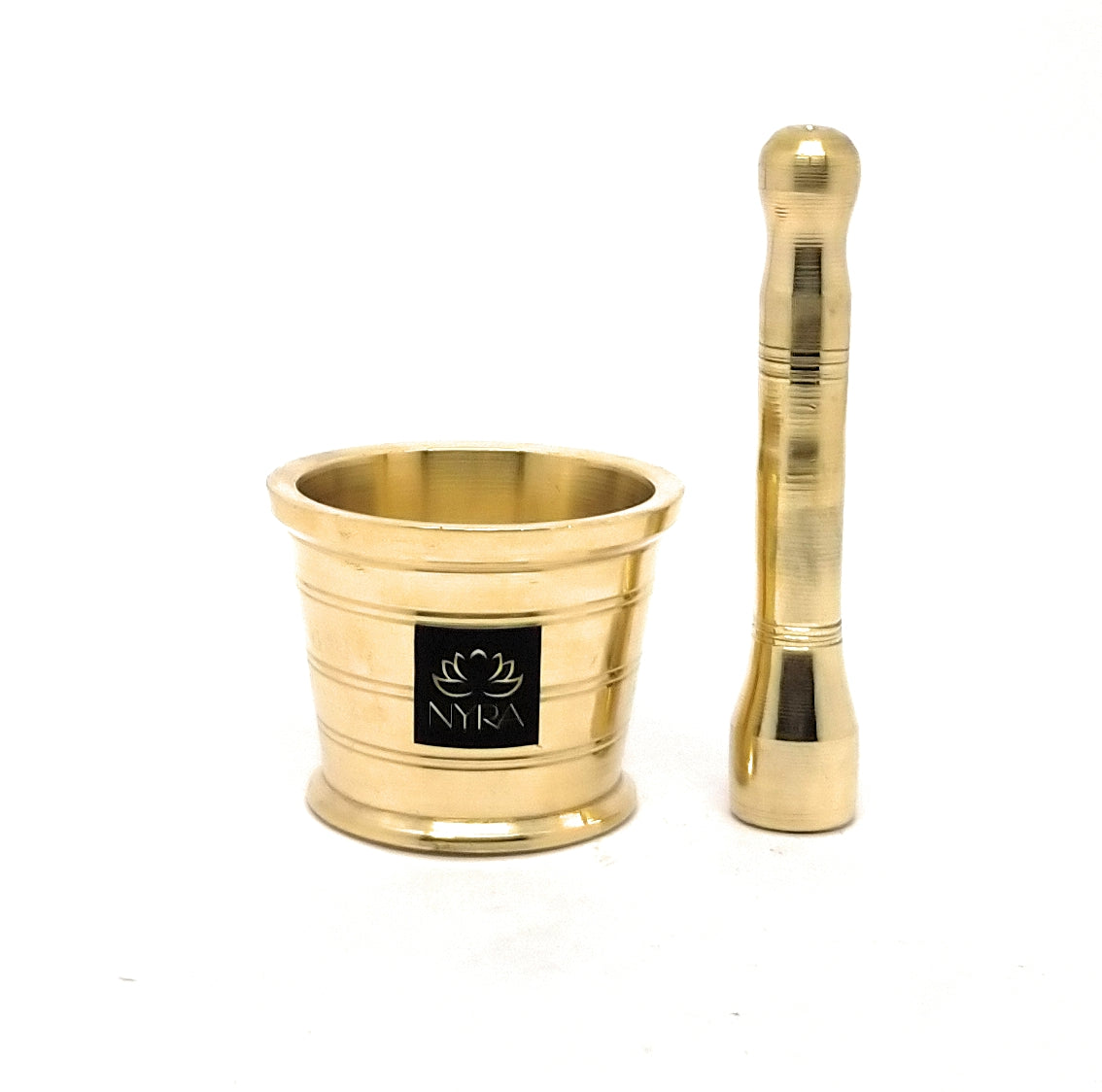 A gold-colored brass mortar and pestle set on a white background, featuring a black square logo plate on the mortar with the brand name 'NYRA'.