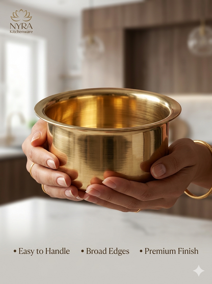 A pair of hands holding a polished brass bowl with a brushed metallic finish, set against a softly blurred kitchen background. The brand logo 'NYRA Kitchenware' is visible in the top left, and feature text at the bottom reads 'Easy to Handle', 'Broad Edges', and 'Premium Finish'.
