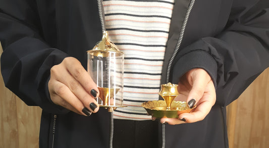 showing in hand Brass Akhand Jyoti Diya with Borosiliate Glass Cover and Agarbatti stand Set/Combo