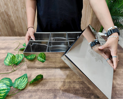 Person opening a stainless steel kitchen drawer with compartments on a wooden surface.