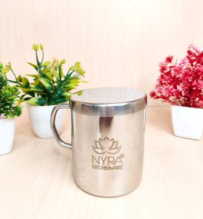 Stainless steel mug with 'Nyra Kitchenware' logo on a light surface with plants in the background