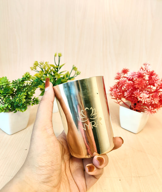 Hand holding a gold metallic cup with floral decorations in the background