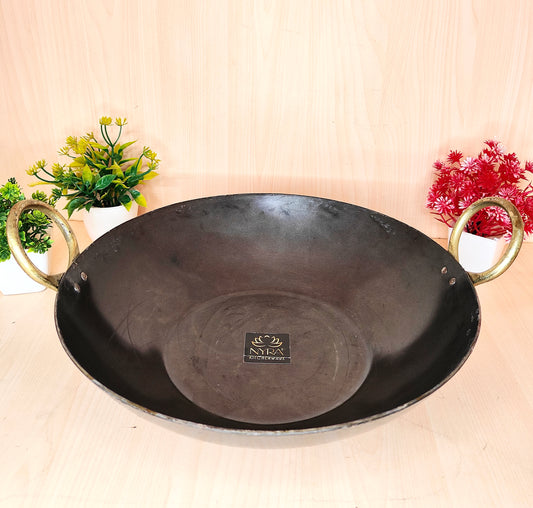 Black wok with gold handles on a beige background