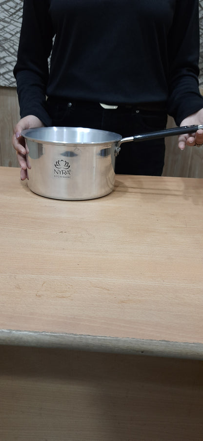 Person holding a metallic container with a lid on a wooden surface