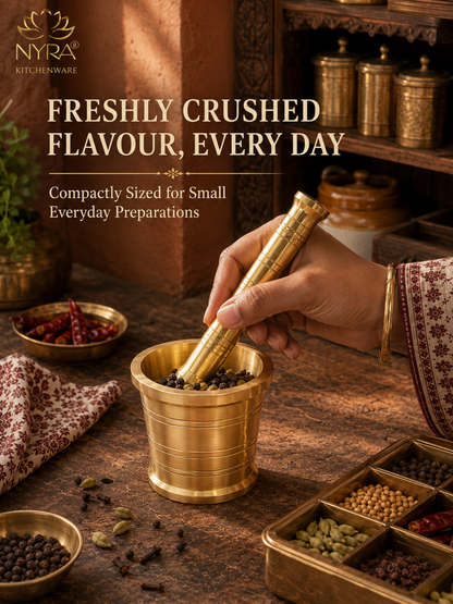 A brass mortar and pestle being used by a hand in a rustic kitchen setting, with spices and containers in the background. Text on the image reads 'NYRA KITCHENWARE' and 'FRESHLY CRUSHED FLAVOUR, EVERY DAY'.