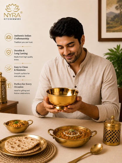 A man in a white shirt holds a shiny brass bowl in a warm, Indian-style dining setting. The scene includes other brass cookware and tableware, with a text overlay on the left highlighting product features under the brand name NYRA KITCHENWARE.