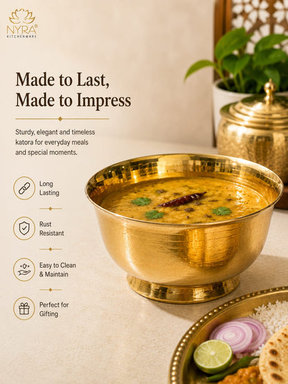 A golden brass katora bowl filled with yellow kofta, shown on a beige tabletop with a plate of food, a potted plant, and a brass pot in the background. Text on the left reads 'Made to Last, Made to Impress' with feature icons for long lasting, rust resistant, easy to clean, and perfect for gifting.