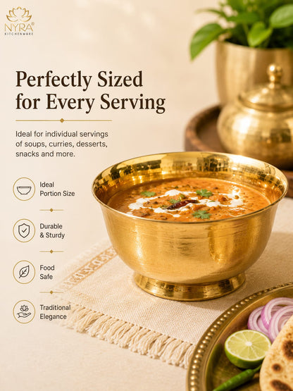 A brass Indian clay pot (kadhai) filled with a rich orange-red curry, presented on a beige textured cloth next to a plate of flatbread, onions, lime, and green chilies. The image features promotional text on the left side and the 'Nyra Kitchenware' logo in the top left corner.