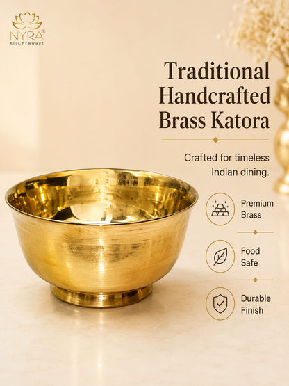 A polished brass katora bowl on a light marble surface with promotional text on a cream background. The text reads 'Traditional Handcrafted Brass Katora' and includes feature icons for premium brass, food safe, and durable finish.