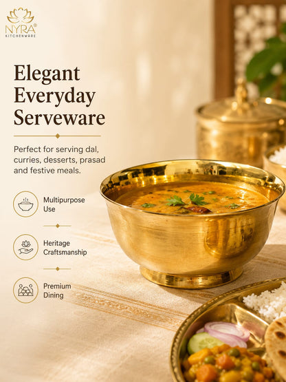 A brass Indian serving bowl filled with curry, styled on a table with rice, pickle, and flatbread, alongside text describing the product as elegant everyday serveware by NYRA Kitchenware.