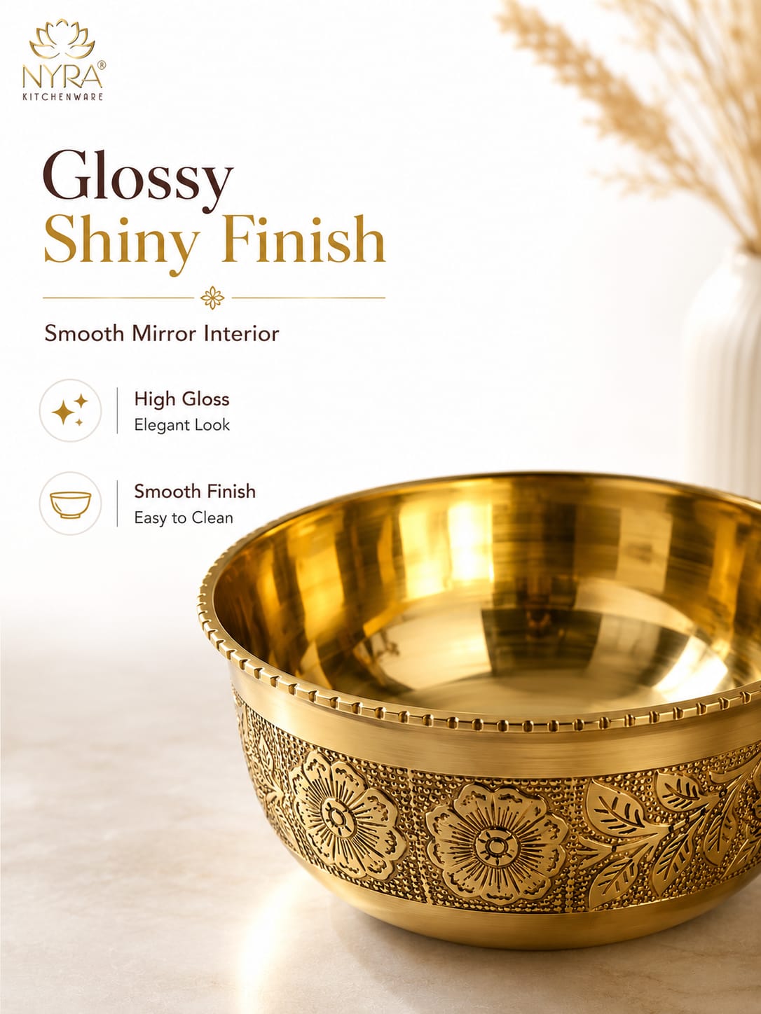 A decorative brass bowl with a shiny golden finish and embossed floral patterns on the exterior, shown on a light beige surface with text describing its glossy interior and finish. The NYRA Kitchenware logo is visible in the top left.