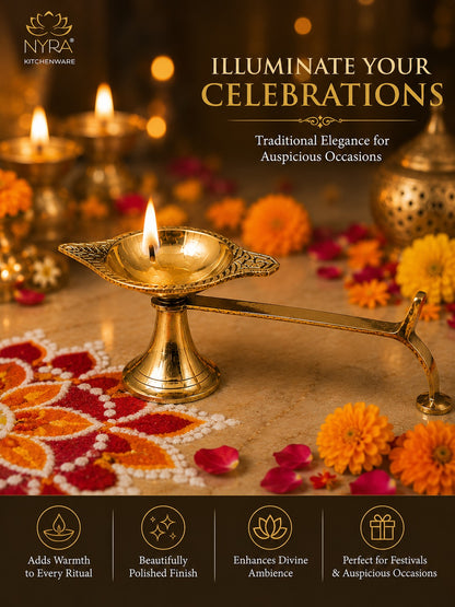 A brass oil lamp (diya) with a lit flame on a decorated surface, surrounded by marigold flowers, lit candles, and festive rangoli, with promotional text and the NYRA Kitchenware logo.