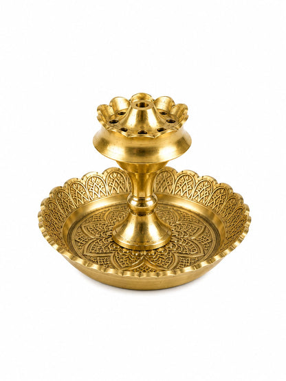 A golden brass double-tiered diya holder with intricate embossed patterns on the base and a scalloped rim, isolated on a white background.