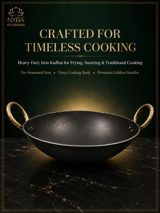 A dark cast-iron kadhai with gold-toned handles and rim, shown on a black marble surface against a dark green background with gold text reading 'CRAFTED FOR TIMELESS COOKING' and the NYRA Kitchenware logo.