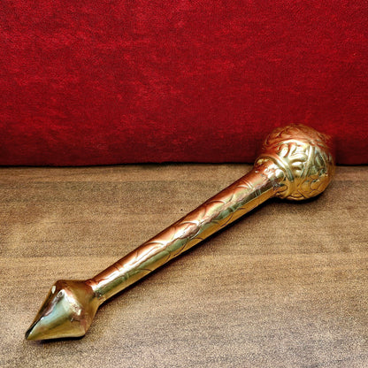 Decorative brass mace on a textured surface with a red background