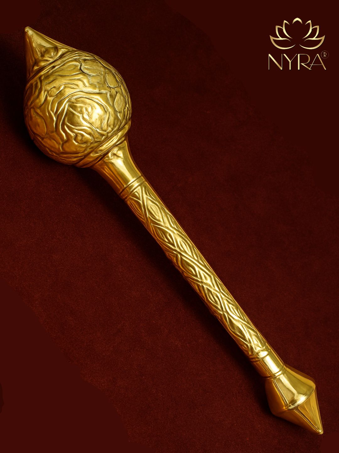 Decorative brass mace with intricate patterns on a dark red background, featuring the brand 'Nyra'.