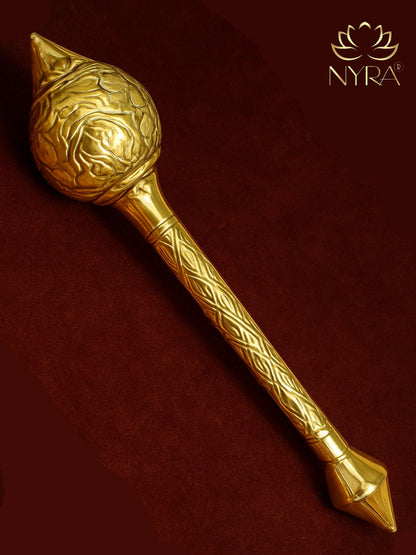 Decorative brass mace with intricate patterns on a dark red background, featuring the brand 'Nyra'.