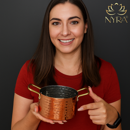 Woman holding a bronze-colored metal cup with 'Nyra' branding in the background