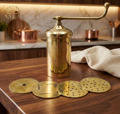 Brass kitchen tool with interchangeable discs on a wooden surface, with 'Nyra' brand visible.